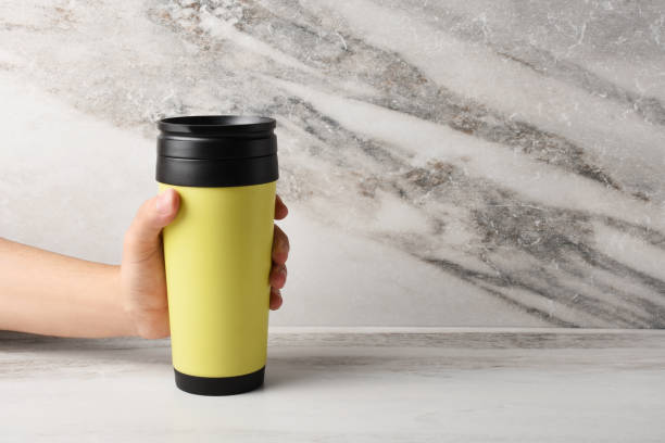 istock A male hand holding a insulated drink container, mug on the marble texture background 1334615085