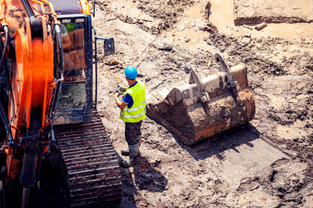 istock A construction worker is standing next to an excavator on a construction site. View from above. 1334615104