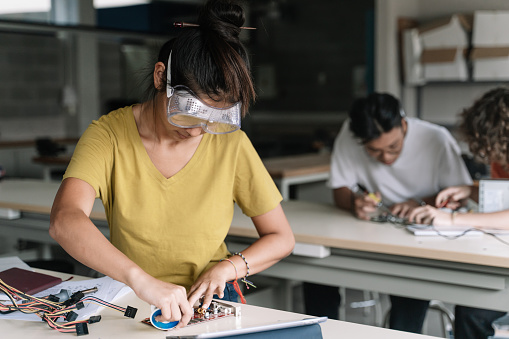 Estudiante adolescente de secundaria asiática con gafas protectoras que trabaja en la placa de circuitos electrónicos en el taller de tecnología científica - Innovación digital en la educación photo