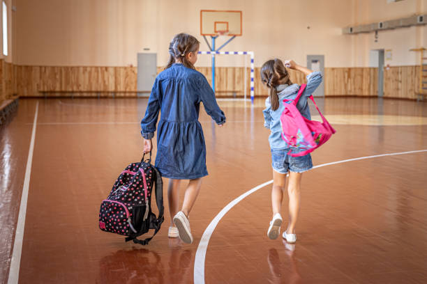 istock Little girls with backpacks in an empty school gym. 1334624471