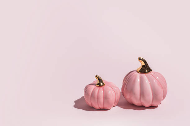 istock Two decorative ceramic pumpkins on pink background in hard light with copy space. 1334624542