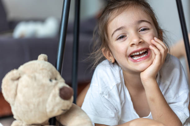 istock Cute little girl laughing lying with a teddy bear 1334624891