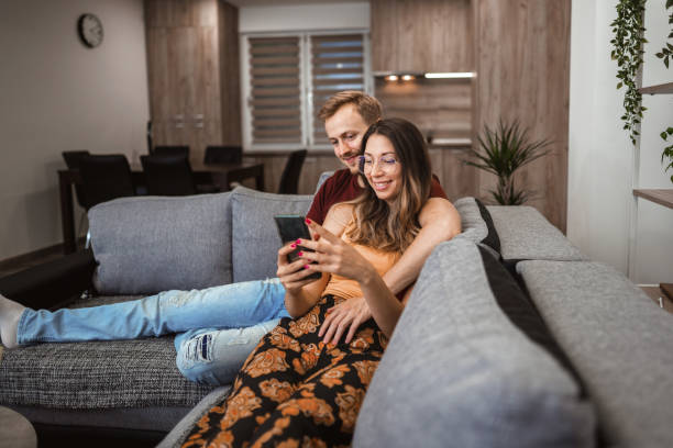 istock Young couple in the living room scrolling on mobile 1334626430