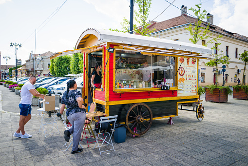 Baia Mare, Romania - 7 August, 2021: color image depicting customers outside a colorful mobile food wagon selling sweet waffles in Baia Mare, Romania.