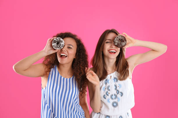 istock Beautiful young women with donuts on pink background 1334627958