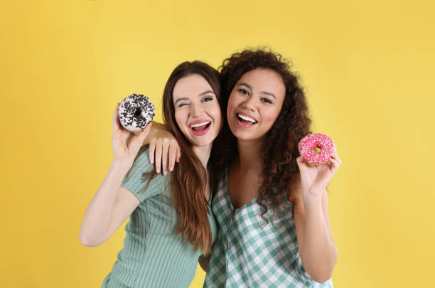 istock Beautiful young women with donuts on yellow background 1334628329