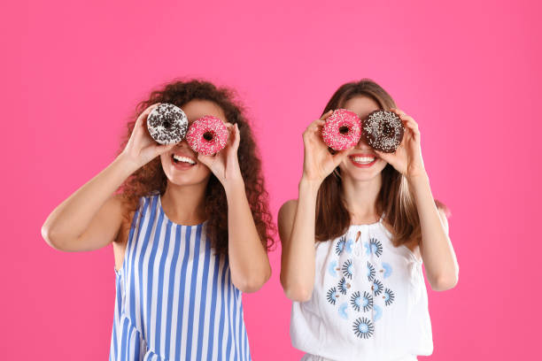 istock Beautiful young women with donuts on pink background 1334628402