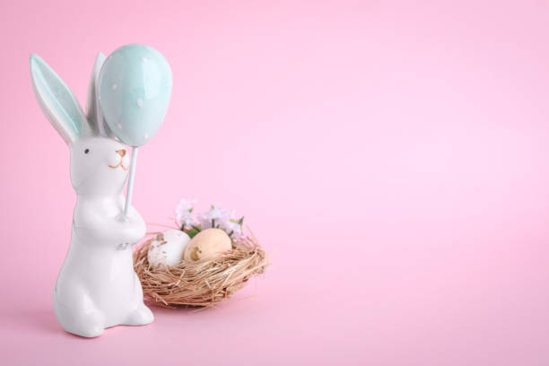 istock Easter bunny figure and nest with eggs on pink background. Space for text 1334631068