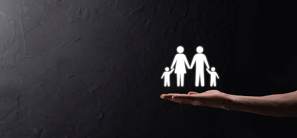 Hand hold young family icon. Family life insurance,supporting and services,family policy and supporting families concepts.Happy family concept.Copy space.mancupped hands showing paper man family.