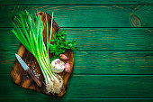 Cutting board with scallion, parsley, garlic and salt. Copy space