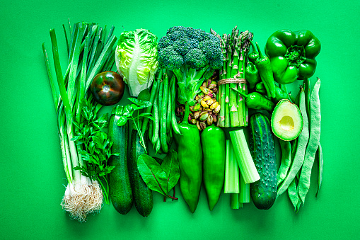 Healthy eating concepts: green background filled with a large number of green vegetables shot from above. The composition includes broccoli, tomato, spinach leaves, green bell pepper, green beans, asparagus, avocado, parsley, pistachio, cucumber, celery and pumpkin seeds among others. High resolution 42Mp studio digital capture taken with SONY A7rII and Zeiss Batis 40mm F2.0 CF lens
