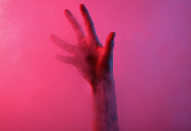 istock Hand in dense smoke with red-blue neon light. Mystical, Halloween theme 1334639039