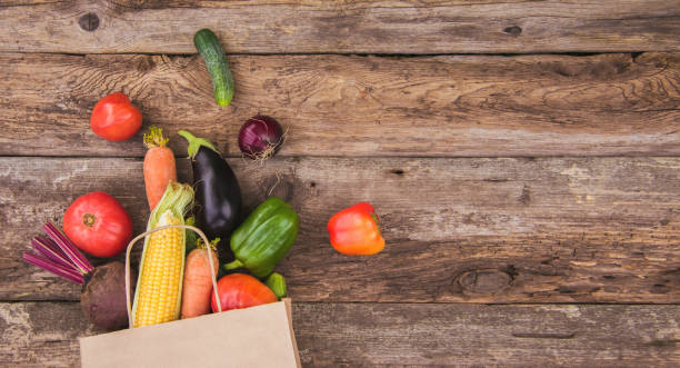 istock A paper bag with scattered vegetables on a wooden background. Copy space 1334642574