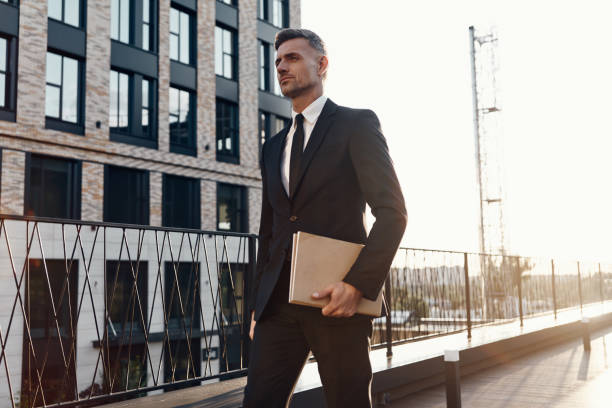 istock Confident mature man in full suit carrying laptop 1334643754
