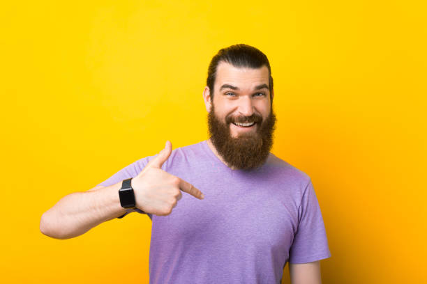 istock Smiling bearded man is pointing at himself over yellow background. 1334643791