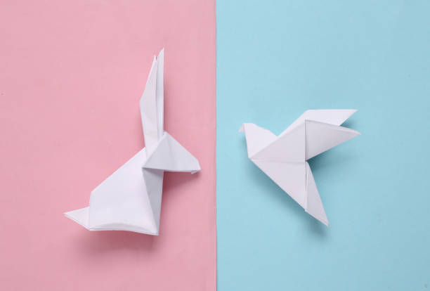 istock Origami rabbit and dove on a blue-pink pastel background. Top view 1334645175