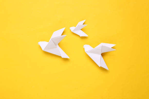 Origami paper doves on a yellow background. Peace symbol stock photo