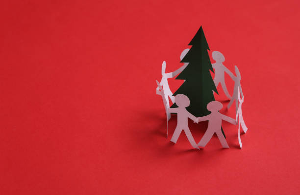 istock Paper chain cutted people around christmas tree on red background 1334645362
