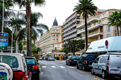A view of the famed Boulevard de la Croisette in Cannes, France along the Mediterranean Sea.  This boulevard has sandy beaches to one side and upmarket retail shops and luxury hotels on the other side.