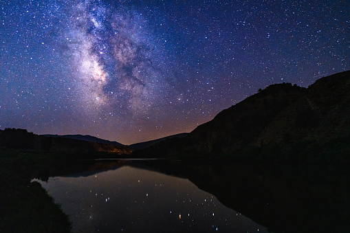 Colorado River Milky Way Galaxy Reflection Landscape - Night astrophotography scenic landscape with dark skies and stars reflecting in calm waters of the Colorado River.