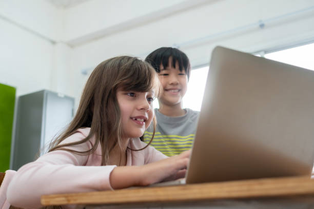 istock Diverse Multi ethnic of students girl and Asian boy enjoying using laptop for learning in classroom at primary school. 1334655754