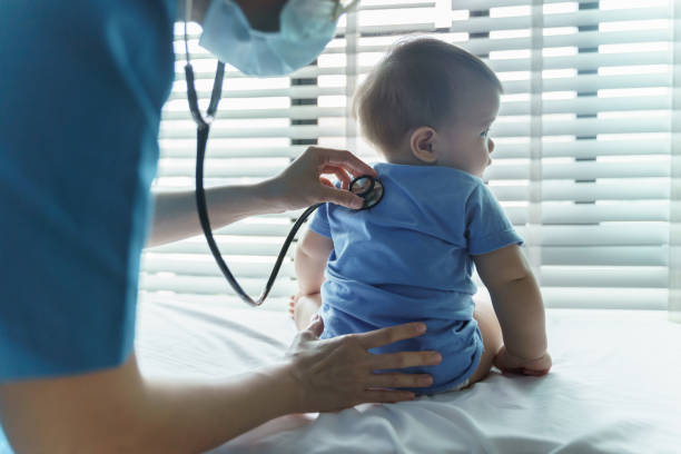 asiatische kinderärztin untersucht ihre kleine babypatientin mit stethoskop im krankenzimmer - kinderarzt stock-fotos und bilder