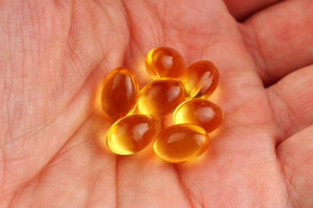 istock Fish oil in capsules in hand on a black background 1334656815