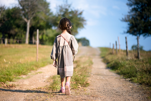 A girl in a rustic dress goes into the distance.