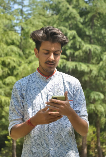 istock Portrait of a Indian handsome young guy standing outside with using mobile phone 1334657987