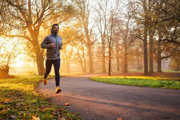 Photo of Adult male runner in park at autumn sunrise