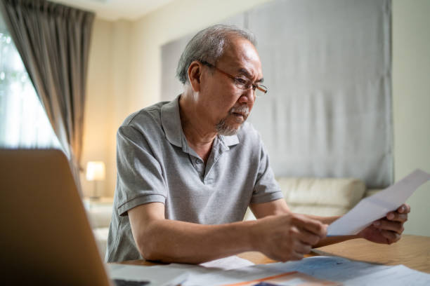 istock Depressed Asian Senior male feeling worried about financial problem. Stressed desperate elderly older man looking frustrated to paperwork and bills think of money debt, budget loss, bankruptcy at home 1334661362