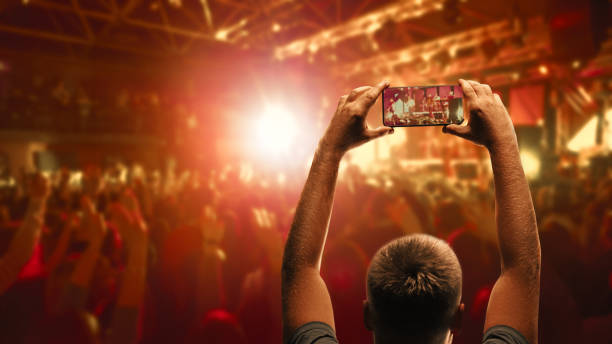 filmación para la memoria. hombre tomando una foto del espectáculo en la sala de conciertos usando un teléfono inteligente. - crowd noise flash fotografías e imágenes de stock