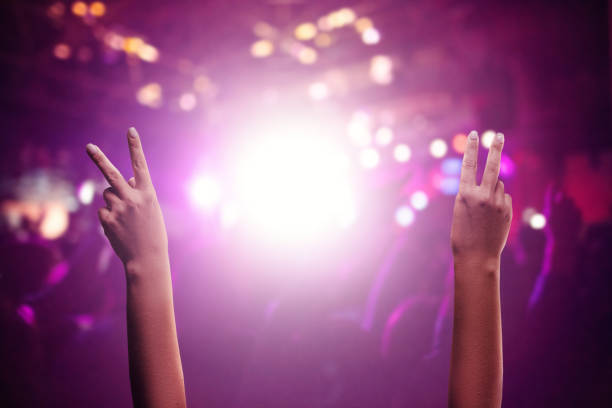 ショーやコンサートを楽しむ。ライブミュージックコンサート中に混雑したホールでvサインを発揮する上げた手 - crowd noise flash ストックフォトと画像