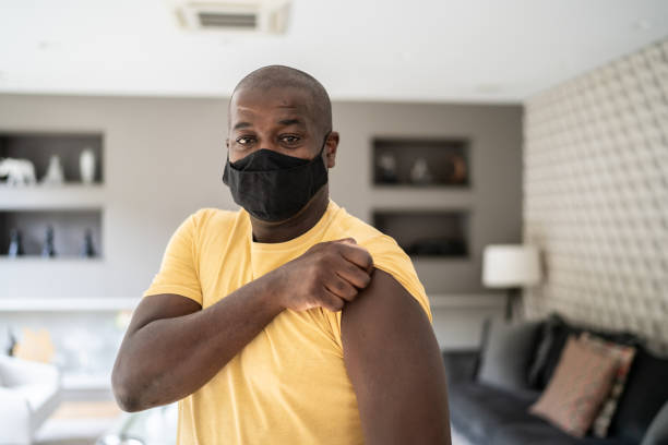 Portrait of a man showing arm for vaccination - wearing protective face mask Portrait of a man showing arm for vaccination - wearing protective face mask rolled up sleeves stock pictures, royalty-free photos & images
