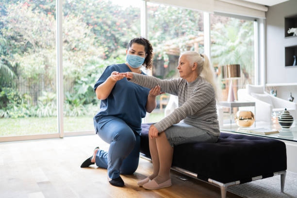 istock Physical theraphist supporting senior woman doing arm exercise at home 1334662850