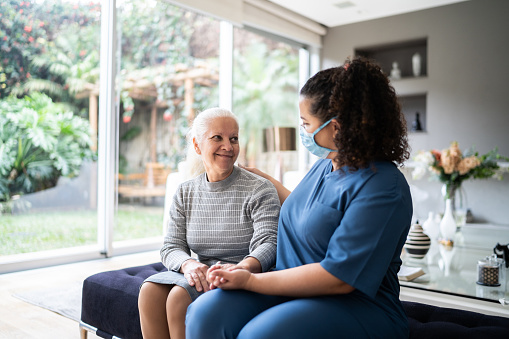 Trabajador de la salud hablando y consolando a un paciente mayor durante una visita domiciliaria photo