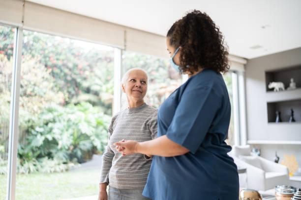 istock Home caregiver helping senior woman walking at home - wearing protecive face mask 1334663152