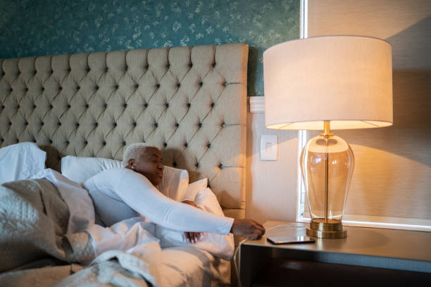 mujer que se va a la cama y apaga la lámpara de cama en casa - sleeping insomnia alarm clock clock fotografías e imágenes de stock