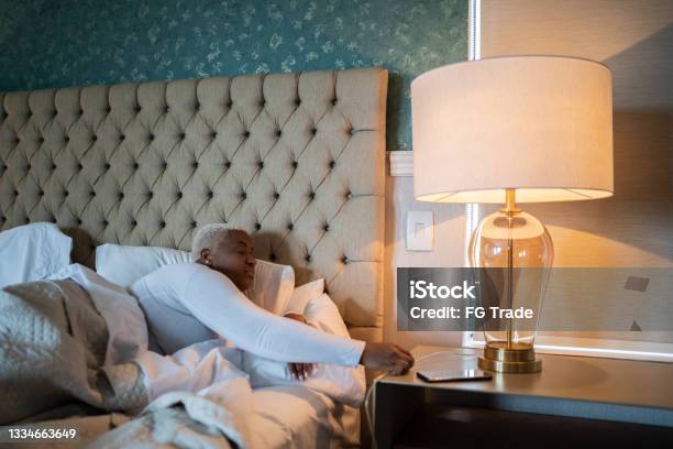 Woman Going To Bed And And Turning Off Bed Lamp At Home Stock Photo - Download Image Now