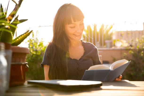 istock Young woman reading a book on terrace at sunset 1334666419