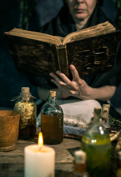 istock Dark Witch at work: black magic woman makes the witchery by mixing herbs, casting the spells, running magic rituals 1334666537