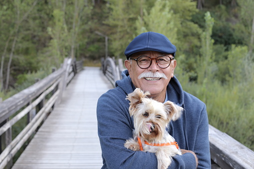 Ethnic senior man with small dog in the park.