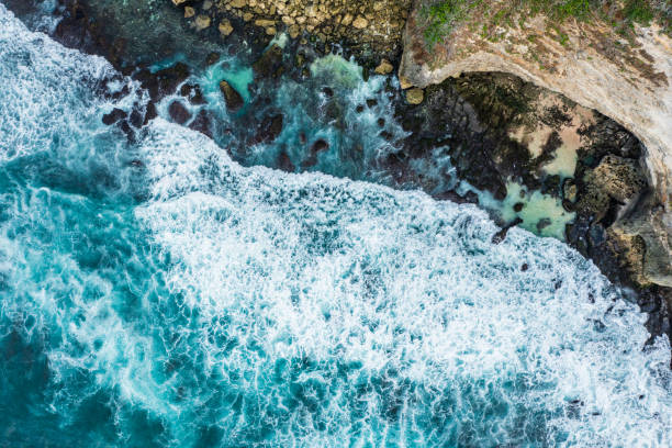istock Ocean waves hitting a rocky beach and cliffs. View from above. 1334668338
