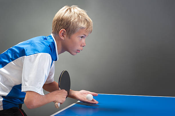 A young boy about to serve in table tennis