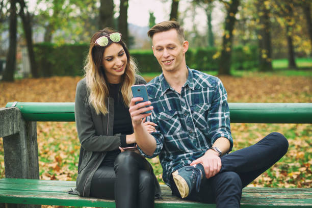istock Young couple browsing photos in park 1334669736