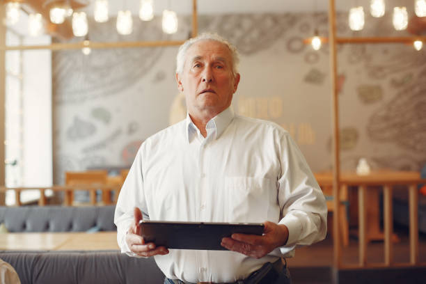 istock Elegant old man in a cafe using a laptop 1334670974