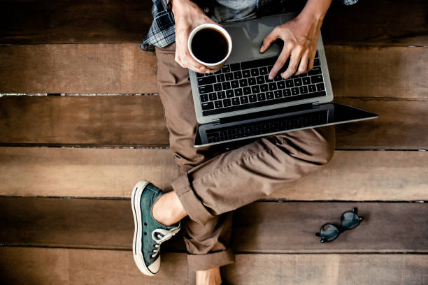 istock Man hand typing keyboard learning and researching course tutor education, online on technology personal computer laptop with coffee cup. Are sitting on the wooden floor. Top view 1334672774