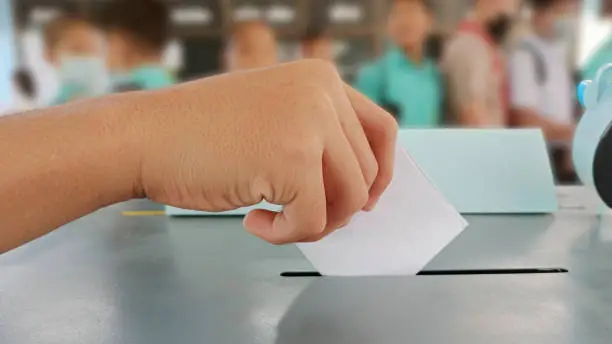 Photo of Students hands voting in the ballot box Voters on Election Day for the student council and the school board