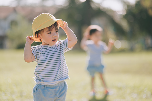 cute asian chinese baby boy wearing yellow hat at public park in the morning