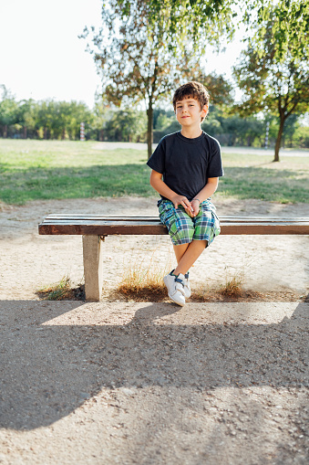 Portrait of school boy sitting on bench after school classes.
